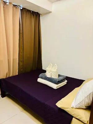 a purple bed with towels and shoes on it at Condotel By RhoiVC in Shell Residences Moa Near Naia Airport in Manila