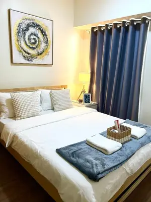 a bedroom with a large bed with blue curtains at CASA SOPHIA Affordable Condo Near Bonifacio Global City BGC CBD in Manila