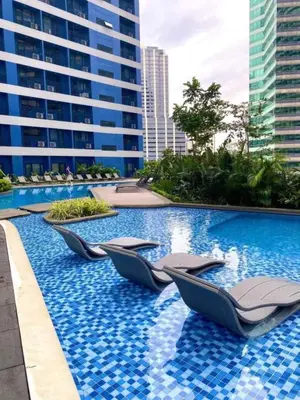 a swimming pool with lounge chairs in a building at Air Residence in Manila