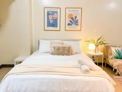 a bedroom with a large white bed with two pictures on the wall at Luxurious Condo Beside Venice Mall #vlrtd20e in Manila