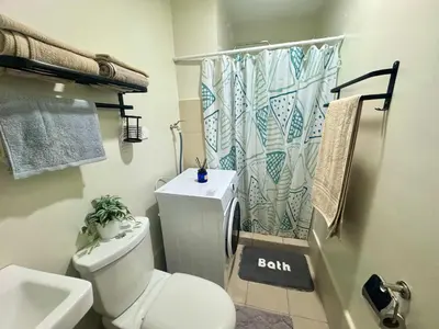 a bathroom with a toilet and a shower curtain at The J-MA UltiEscape Charm Residences Condo in Manila