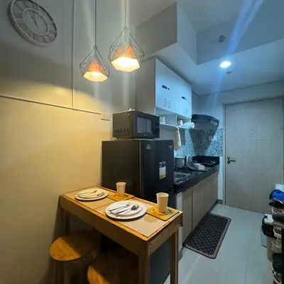 a kitchen with a wooden table with plates on it at The J-MA UltiEscape Charm Residences Condo in Manila
