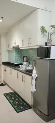 a kitchen with white cabinets and a stainless steel refrigerator at Moa Staycation pasay by mj in Manila