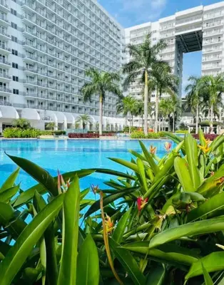 a resort swimming pool with palm trees and a large building at shell staycation in Manila