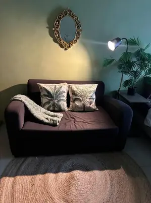 a couch in a living room with a mirror at Tropical Haven in Makati CBD in Manila