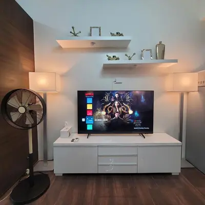 a living room with a flat screen tv on a white cabinet at Air Residences - Pool View Balcony near Airport - 4576 in Manila