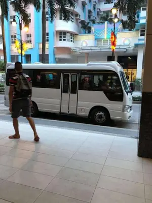 a man walking on a sidewalk next to a white bus at Ivy Condotels Unit -101Newport Boulevard in Manila