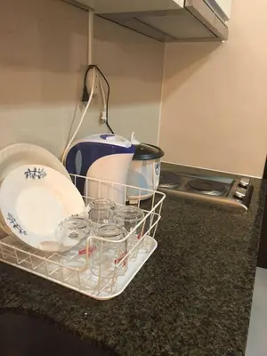 a dish drying rack with dishes and plates on a kitchen counter at Ivy Condotels Unit -101Newport Boulevard in Manila