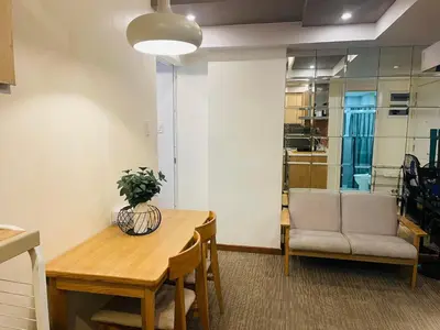a living room with a table and a couch and a chair at KYH STAYCATION 2BR by Azure Residences Near Airport in Manila
