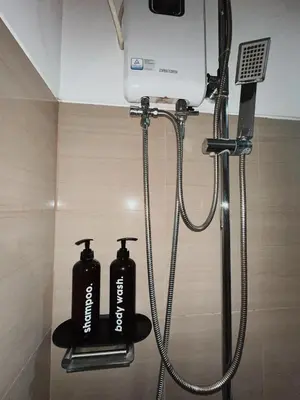 a shower with two black shampoo bottles in a bathroom at 1BR Shore Residences near Mall Of Asia in Manila