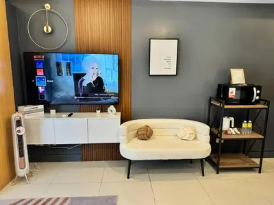 a living room with a tv and a white chair at Studio Unit McKinley Hill Taguig cd21H in Manila