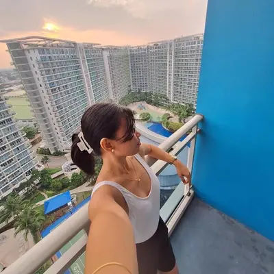 a woman standing on a balcony looking at the city at Spacious 1Bedroom Condotel Resort in Manila