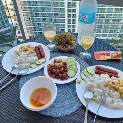 a table with plates of food and glasses of drinks at Spacious 1Bedroom Condotel Resort in Manila