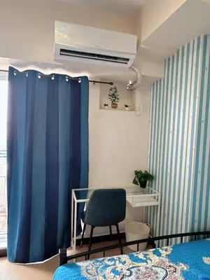 a bedroom with a blue curtain and a chair at Torre De Manila in Manila