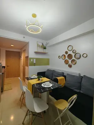 a living room with a couch and a table and chairs at Pasay Shore Residences Staycation in Manila
