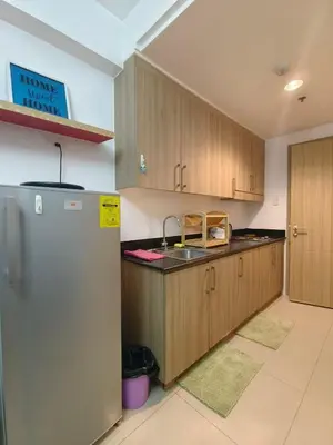 a kitchen with wooden cabinets and a stainless steel refrigerator at Pasay Shore Residences Staycation in Manila