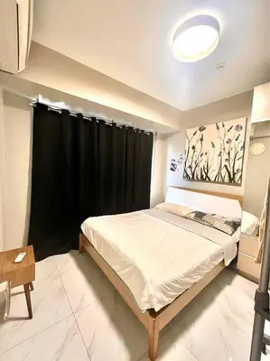 a bedroom with a large bed and a black curtain at Cozy 1-BR Retreat Near MOA Pool view in Manila