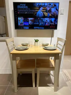 a wooden table with two chairs and a television at Chic & Cozy Apartment Near BGC with Home Theater Setup in Manila