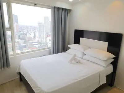 a bedroom with a white bed with a large window at Alpha Grandview Malate Condo 2004 in Manila