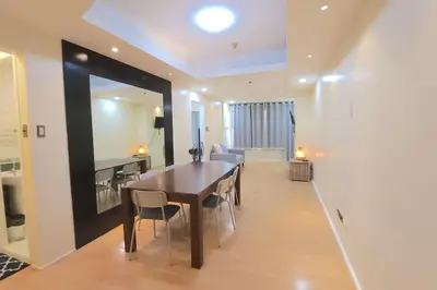 a dining room and living room with a table and chairs at Alpha Grandview Malate Condo 2004 in Manila