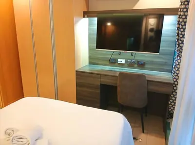 a bedroom with a desk with a television and a bed at Comfy 1BR At Uptown BGC in Manila