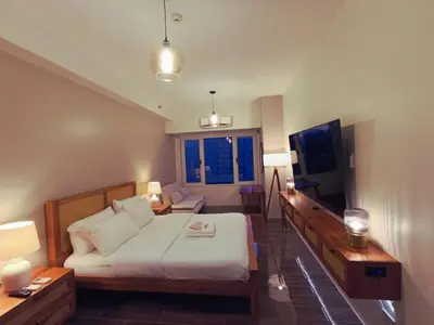a bedroom with a bed and a couch and a tv at Air Residence- Makati in Manila