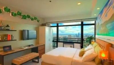 a bedroom with a bed and a desk and a window at Gramercy Century City Makati in Manila
