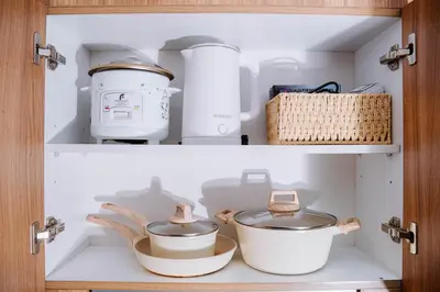 two shelves with pots and pans in a cabinet at Oranje Suite Near Naia Terminal in Manila