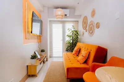 a living room with an orange couch and a window at Oranje Suite Near Naia Terminal in Manila