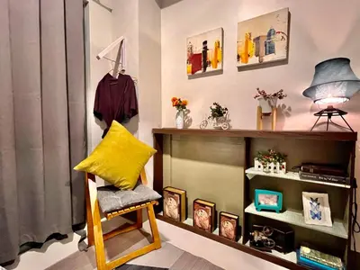 a room with a chair and a shelf with pictures at Heart of Makati in Manila