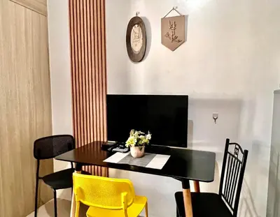 a dining room table with yellow chairs and a clock at Cozy Home in Mall of Asia - Aseana Pasay in Manila