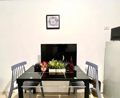 a dining room table with two chairs and a tv at Cozy Home in Mall of Asia - Aseana Pasay in Manila