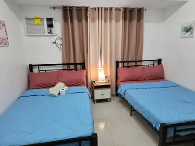 two beds in a room with a stuffed animal between them at Staycation near US Embassy in Manila