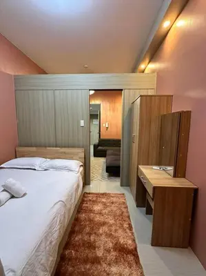 a bedroom with a bed and a desk and a room at Cozy orange room at shore in Manila