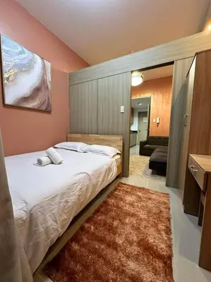 a bedroom with a large bed and a rug at Cozy orange room at shore in Manila