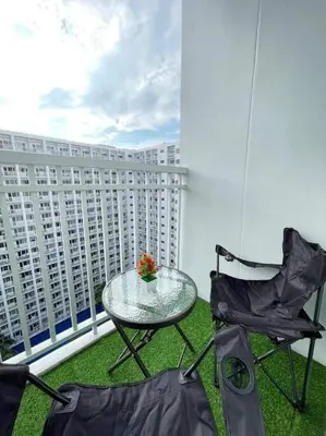 a table and two chairs on a balcony with a building at Shore Residences Staycation by K in Manila