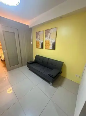 a black couch in a room with a yellow wall at Cozy shore 1 residences in Manila