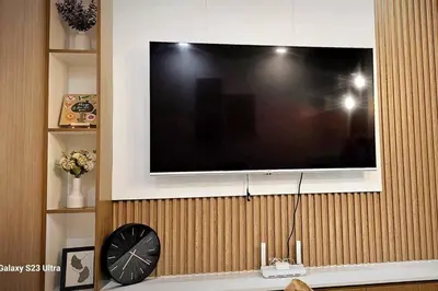 a flat screen tv hanging on a wall with a clock at 1BR self-contained CONDO in Makati with amenities! in Manila