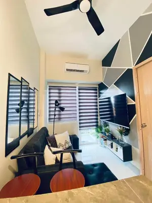 a living room with a black couch and a ceiling fan at Jazz Cozy Abode in Manila