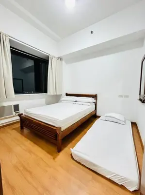 two beds in a room with a large window at Budget Accommodation at Ace Suites by the Famous Indoor Water Spa in Manila