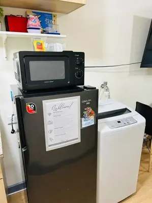a microwave sitting on top of a refrigerator at 1BR Calathea Place nr Airport, Netflix,50mbps Wifi in Manila