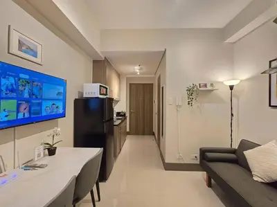 a living room with a couch and a refrigerator at 1BR Condotel with Balcony at FAME Residences #FM58 in Manila