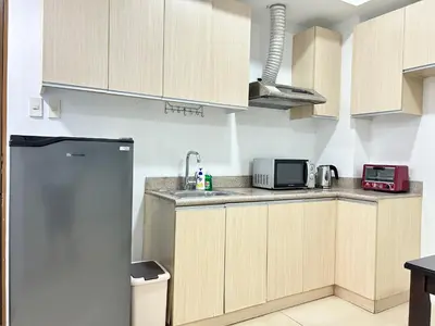 a kitchen with wooden cabinets and a refrigerator at Budget Twin-1Bedroom at Ace Suites in Manila
