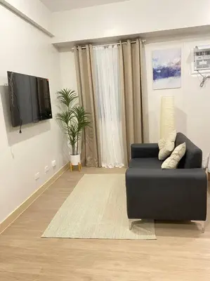 a living room with a black couch and a flat screen tv at SMDC Park Residences near SM City Sta Rosa unit 1 in Ibaba