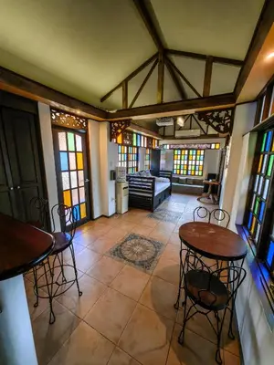a living room with two tables and chairs and stained glass windows at Cozy Las Pinas Haven with Big Garden, Pet Friendly - Near Super Market and the Airport in Manila