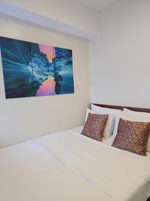 a white bed with pillows and a painting on the wall at Cozy 2BR 2BA 2 Balconies Manhattan Heights Cubao in Manila
