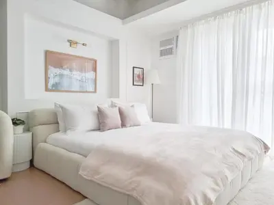 a white bedroom with a large bed and a window at King Bed, Washer, Air Dry, Sauna, Gym & Pool Access, FAST Wi-Fi, Elegant Studio, Near Venice Grand Canal Mall, Walking Distance Britsh Embassy, 5 min drive to BGC, 10 min drive to Manila Airport NAIA 3 in Manila
