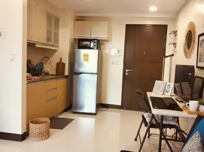 a kitchen with a refrigerator and a table with a laptop at Cozy Home in BGC in Manila