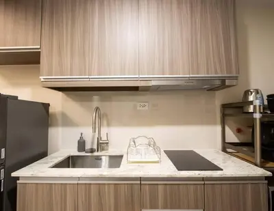 a kitchen with a sink and wooden cabinets at The Room of Requirement in Manila