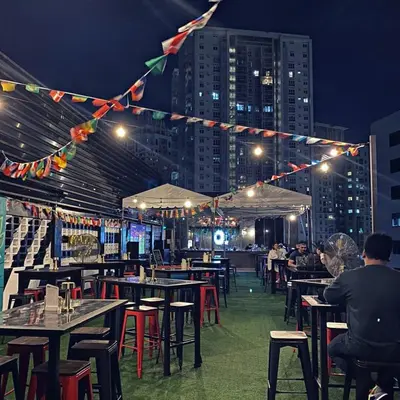 a restaurant with tables and chairs and people at night at Condotel 1 Bedroom Across SM Aura in Manila